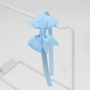 Détail en gros plan du serre-tête nœud ruban bleu clair, mettant en valeur sa texture et sa finition.