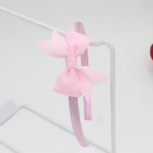Détail de serre-tête nœud ruban gros-grain rose, accessoire cheveux style doux.