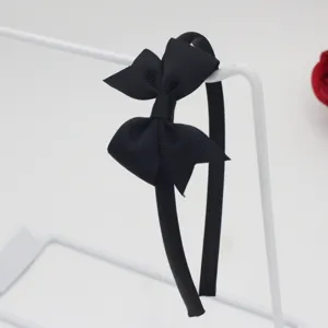 Gros plan sur un serre-tête nœud ruban noir montrant le tissu texturé et la forme.
