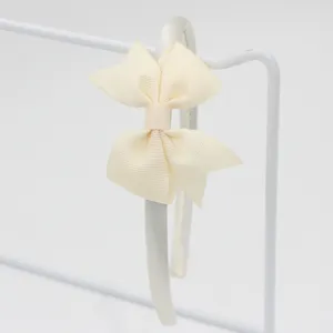 Gros plan d'un élégant serre-tête nœud ruban blanc crème sur support, texture en tissu fin.