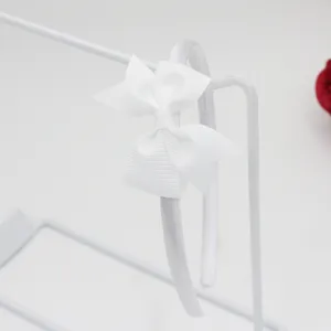 Vue détaillée d'un serre-tête nœud en ruban gros-grain blanc, simple et polyvalent pour tous.