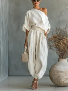 Detail view of elegant off-shoulder top and loose casual trousers set in solid beige tone.
