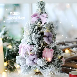 Mini frosted desktop Christmas tree with purple bows and gift boxes for holiday home decor.
