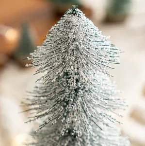 Dettaglio ravvicinato di albero di Natale in miniatura floccato con perle di neve realistiche.