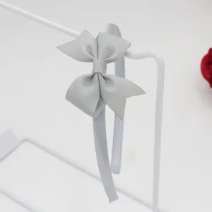 Vue détaillée d'un serre-tête nœud en ruban gros-grain uni minimaliste, couleur gris clair.
