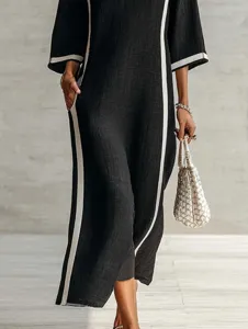 Detailed view of the elegant black long dress with contrast white side stripes and pockets.