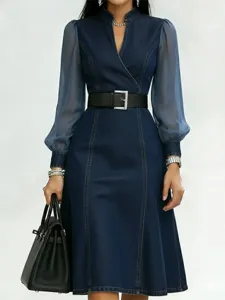 Detailed view of the denim midi dress with sheer long sleeves, stand collar and waist belt.