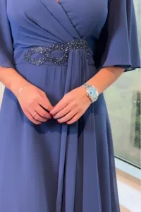 Elegant blue maxi dress detail featuring a V-neck, long sleeves, and a beaded waist.