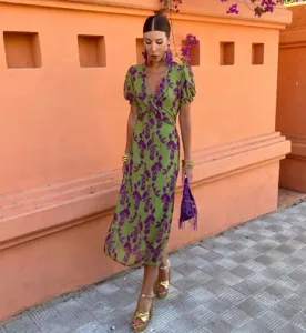 Vue détaillée en extérieur de la robe midi florale verte montrant le col en V élégant.