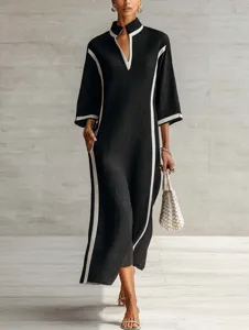 Details of the elegant black maxi dress with white trim, stand collar, and long sleeves.
