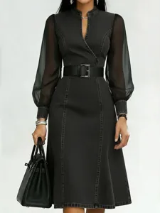 Detailed view of a stylish black denim long sleeve dress with sheer sleeves and wide belt.