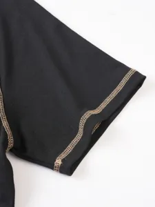Black short sleeve top detail showcasing contrast beige wavy stitching craftsmanship.