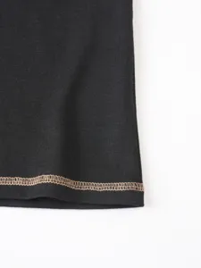Close up of black fabric hem with contrast overlock stitching detail for summer apparel.