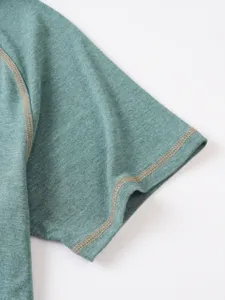 Green cotton linen polo shirt short sleeve detail view showing contrast stitching and fabric texture.