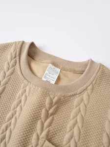Gestructureerde trui ronde hals stof detail met kabelsteek patroon en neklabel close-up.