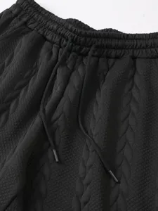 Men's black casual shorts detail, elastic drawstring waist, textured jacquard fabric style.
