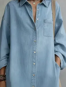 Close-up detail of casual light blue denim shirt dress, lapel collar, single-breasted buttons.