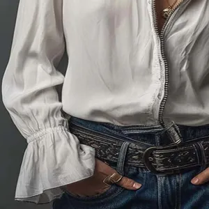 Detail view of a stylish white long sleeve blouse with zipper and ruffled cuffs, paired with jeans.