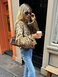 Close-up street style shot featuring a chic leopard print furry short jacket in urban setting.