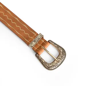 Close-up detail of vintage belt featuring ornate engraved buckle and gold embroidery.