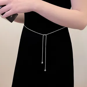 Gros plan d'une chaîne de taille délicate en strass argenté sublimant une élégante robe noire.