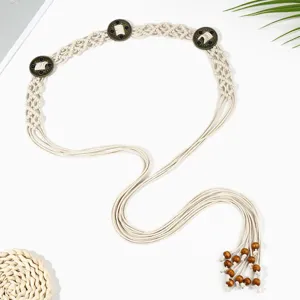 Détail de la ceinture tressée style bohème avec des boucles en métal et perles en bois.