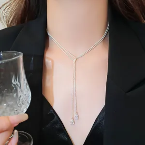 Gros plan détaillé sur le collier Y argenté en strass étincelant porté élégamment.