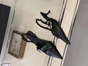 Black patent leather slingback heels with pointed toe, crossover straps and silver buckle.