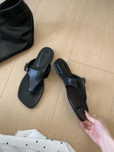 Vue détaillée de sandales plates noires entre-doigts, style rétro été avec boucle métallique.