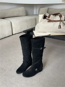 Vista detallada de botas altas de ante negro con correas de hebilla y diseño suave para mujer.