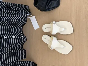 Sandales plates entre-doigts pour femmes associées à un gilet rayé, look d'été élégant.