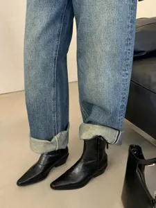 Stylish pointed toe short boots paired with cuffed denim jeans for a vintage retro fashion look.