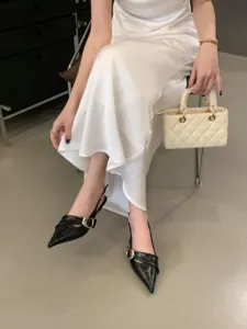 Women fashion outfit set including white slip dress black pointed heels and quilted handbag.