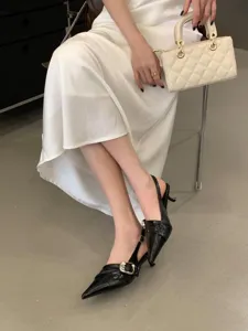 Detail view of elegant black pointed toe slingback heels with metal buckle and slim heel design.