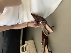 Dark brown pointed slingback kitten heels close-up, textured finish with metallic buckle detail.