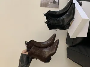 Detail view of retro pointed-toe chunky heel western ankle boots in black and brown leather.