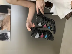 Vue détaillée de sandales noires à talons hauts aiguilles et lanières ornées de strass.