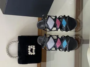 Vue détaillée de sandales à talons hauts noires ornées de strass et sac à main en velours.