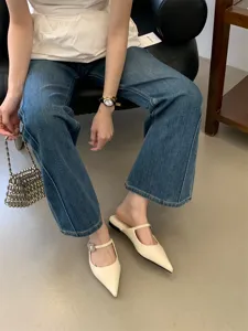 Gros plan détaillé de ces mules plates à bout pointu avec élégante boucle en cristal et fine bride.