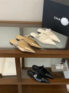 Gros plan détaillé de mules plates à bout pointu avec lanière à boucle strass sur étagère.