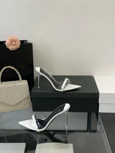 Close detail shot of white pointed transparent PVC strap high heel mules with metal buckle.