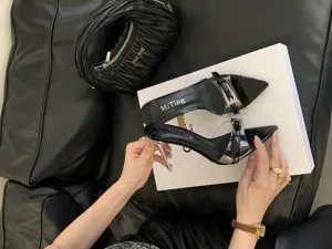 Detailed view of women's black pointed toe stiletto high heels with clear straps and buckle.
