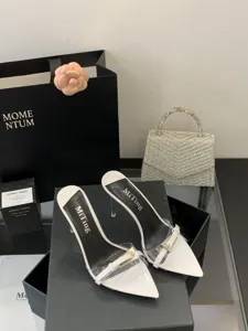 Detail view of white pointed toe high heel mules with clear straps, stiletto heel and elegant buckle.