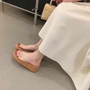 Close-up detail of clear strap cork wedge sandals worn by model in elegant summer outfit.