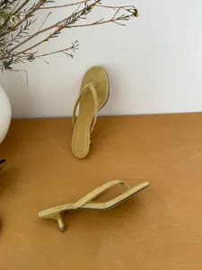 Close-up detail of stylish yellow thong kitten heel sandals, showcasing minimalist design.