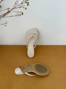 Detail view of stylish beige thong kitten heel sandals showing sole and printed logo.
