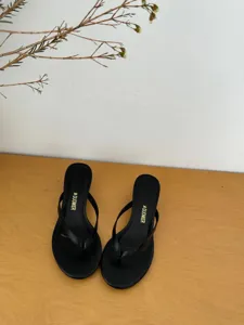 Detailed view of elegant black high-heel thong sandals, showcasing the minimalist strap and slim heel.