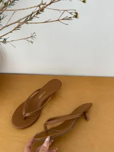 Brown thong high heel sandals detail shot, minimalist summer outdoor footwear with kitten heel.