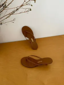 Women's minimalist thong kitten heel sandals in brown, elegant summer footwear detail shot.