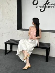 Detail view of stylish minimalist thong high heel sandals worn by model in chic showroom setting.